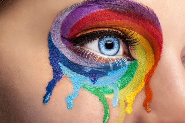 Flowing colors on an eye in fashion stage make up. Rainbow of color spectrum. Blue eye. Close up details. Macro shooting. Fashion on stage make up. Vibrant colors. colored lashes for lgbt pride month