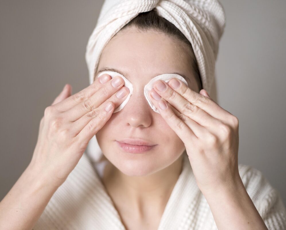 Woman using cotton pads to clean her eyes by lash glue. DIY lash extensions. LavisLash US